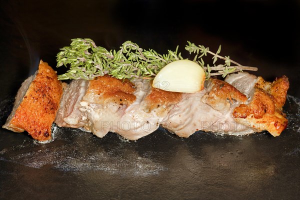 Sliced roast duck breast with fresh thyme and a clove of garlic