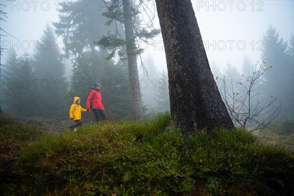 Mum and her little son go on a mountain trail in wet autumn weather. They are accompanied by a dog. Polish mountains