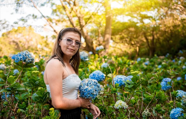 Smiling woman in a hydrangea field. Portrait of young woman in a hydrangea garden