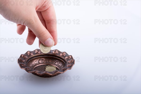 Hand giving away money to a metal bowl