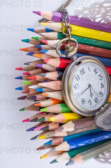 Retro style classic pocket watch and color pencils on white background