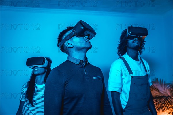 Group of young people with vr glasses in a virtual reality game in a blue light