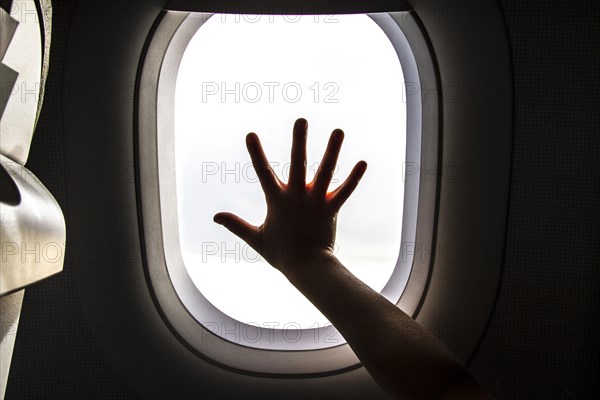 Aircraft window and hand of a child