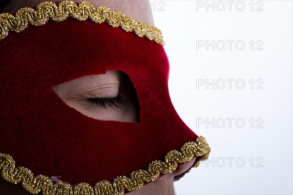 Child looks through carnival mask on liwhite background
