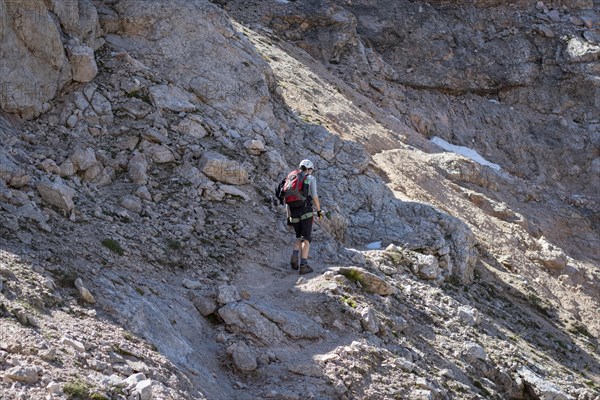 Tourist crossing the via ferrata trail with equipment in the dolomites. Dolomites