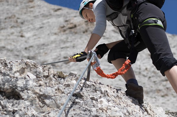 Climbing along a steel line on the via ferrata route in the dolomites. Dolomites