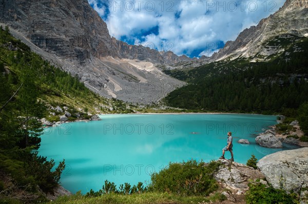 Tourist posing for a photo against the background of the beautiful Lago di Sorapis lake in the Italian Dolomites