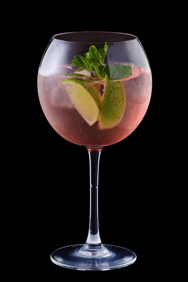 Cold sangria with lime and mint in a wine glass isolated on black background