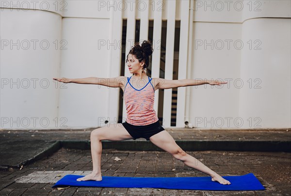 Girl practicing yoga Warrior II pose outdoors. Latin woman doing yoga warrior pose outdoors. Young woman doing yoga virabhadrasana II outdoors
