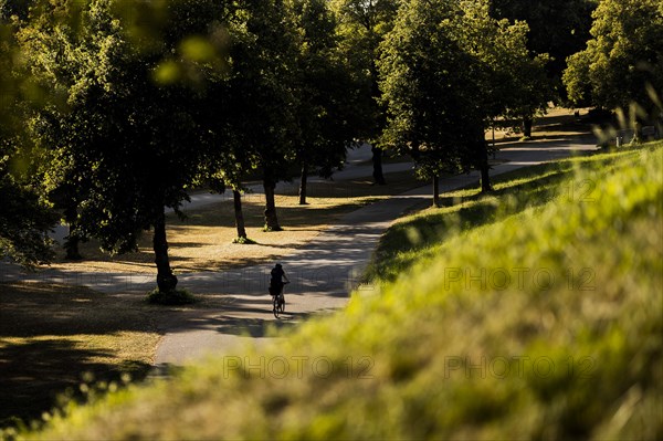 A woman rides her bike through the Olympic Park in Munich