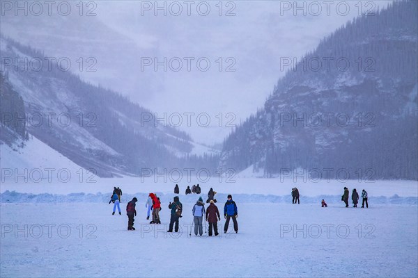 Ice skaters on the frozen mountain lake Lake Louise near Castle Hotel Chateau Lake Louise