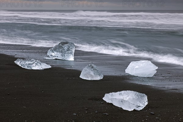 Melting blocks of ice washed on beach along the Atlantic Ocean coastline at Breidamerkursandur black sands in winter