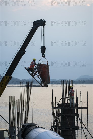 Construction workers busy build pillars of a bridge in the banks of Brahmaputra river on April 3