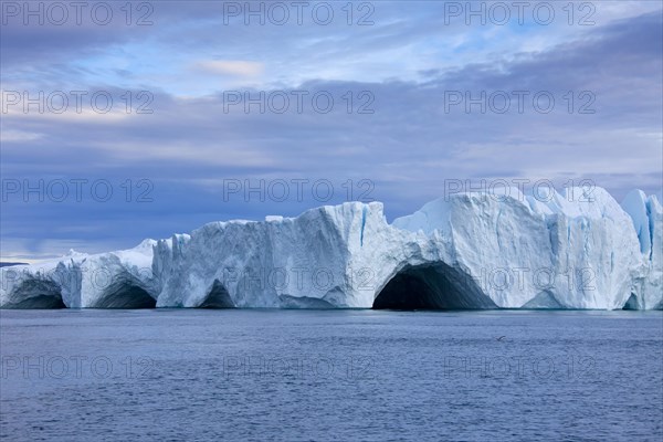 Caves in iceberg at the Kangia icefjord at sunset