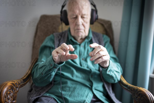 Old man in nursing home conducts to music