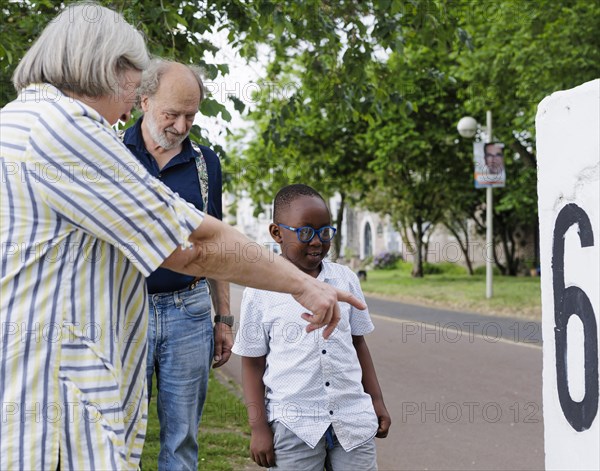 Temporary grandparents. Elderly couple volunteer to look after a boy from Africa for a few hours a week.