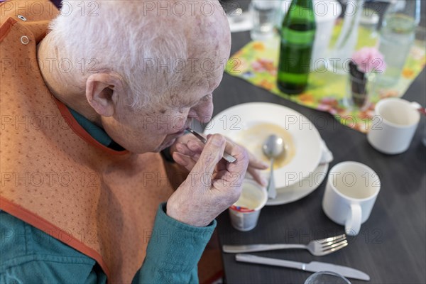 Old man in nursing home spooning a dessert