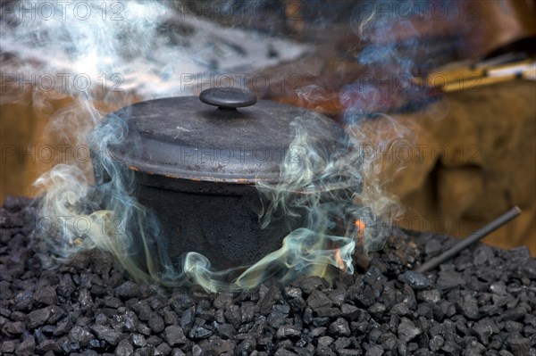 Cast iron pot on the charcoal for tempering the forged material