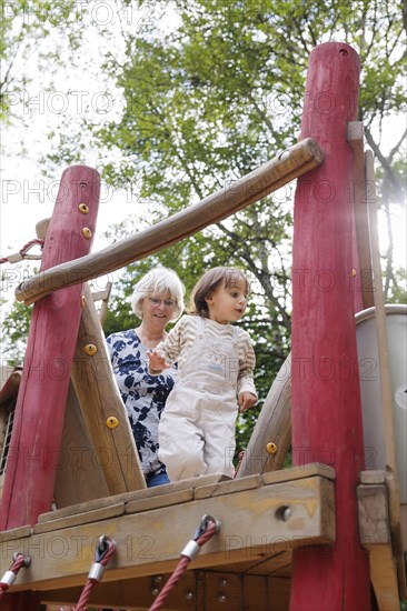 Volunteer. Temporary grandmother with a child in the playground.