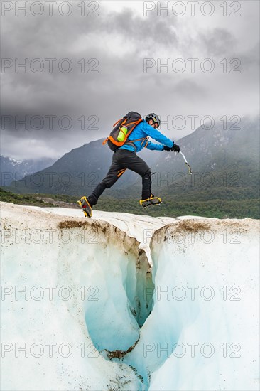 Hiker jumps over an ice crevasse