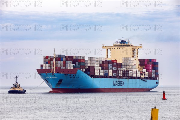 Tugboat guides the container ship Maersk Luz to the unloading berth at Ueberseehafen