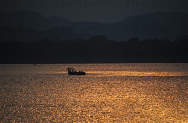 Fishermen row their boat in Brahmaputra river during sunset on April 3
