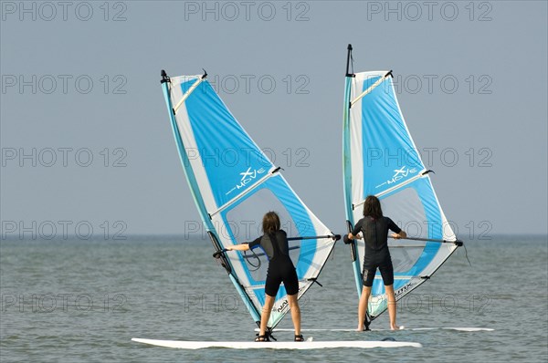 Two young girls windsurfing along the North Sea coast