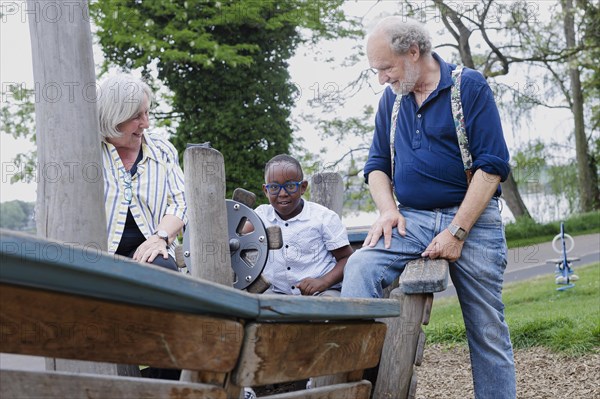 Temporary grandparents. Elderly couple volunteer to look after a boy from Africa for a few hours a week.