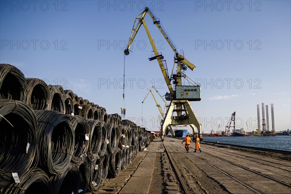 Dock workers walk past rolls of steel wire on the quay in Constanta harbour. Constanta