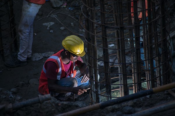 Construction workers busy build pillars of a bridge in the banks of Brahmaputra river on April 3