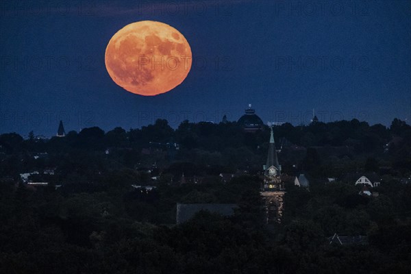 The so-called strawberry moon looms as it rises in Berlin