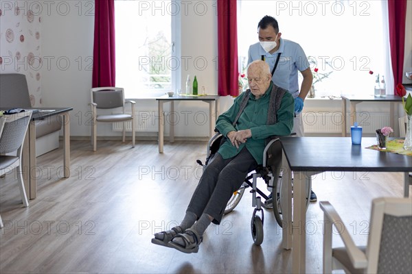 Geriatric nurse pushing a wheelchair in a nursing home