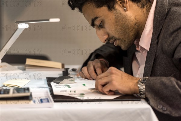 Man sorts small cut slivers from emerald