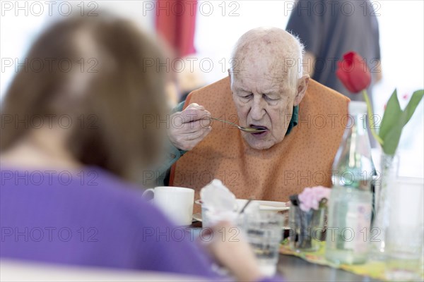 Old man in a nursing home spooning soup