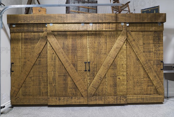 Aged antique style pine wood closet with sliding barn doors in two-car garage inside hybrid timber frame home