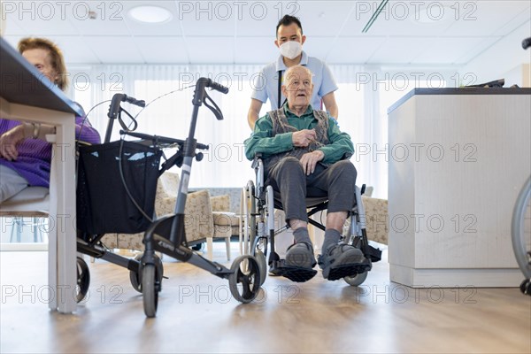 Carer with man in wheelchair in nursing home