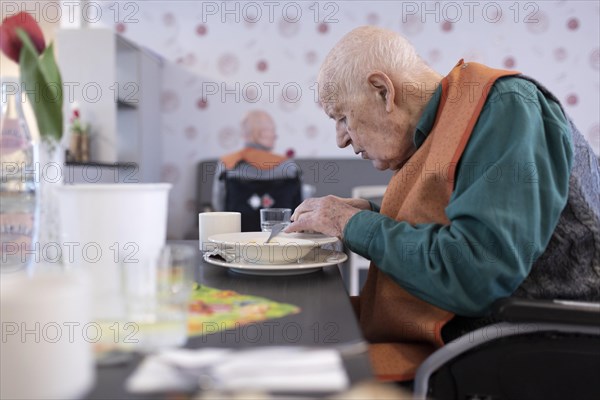 Old man in a nursing home spooning soup