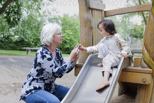 Volunteer. Temporary grandmother with a child in the playground.