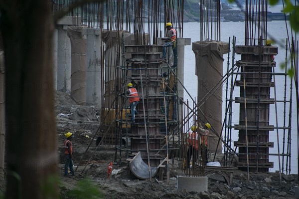 Construction workers busy build pillars of a bridge in the banks of Brahmaputra river on April 3