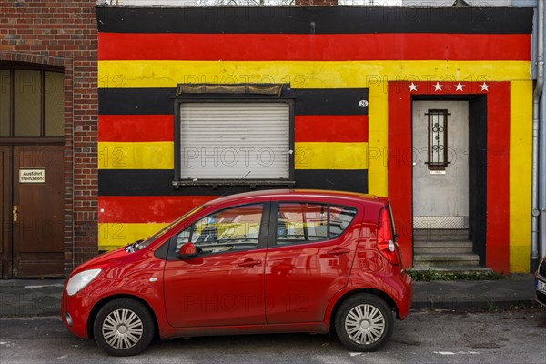 Front of a residential building in the German national colours black-red-gold and 4 stars above the entrance door