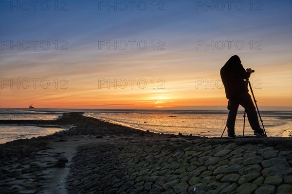 Tourist with camera during sunset on the Trischendamm