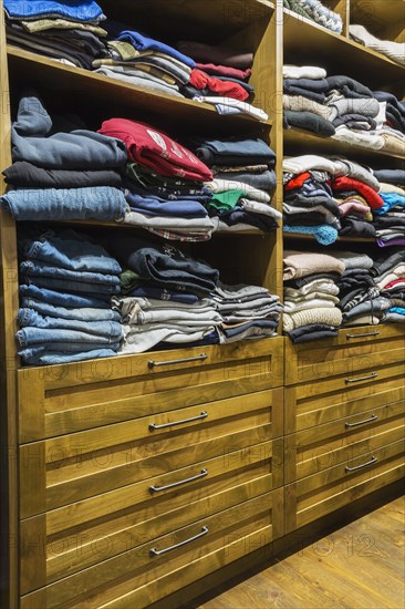 Antique finished chest of drawers with integrated shelves and exposed assorted clothes in walk-in closet in main bedroom inside home