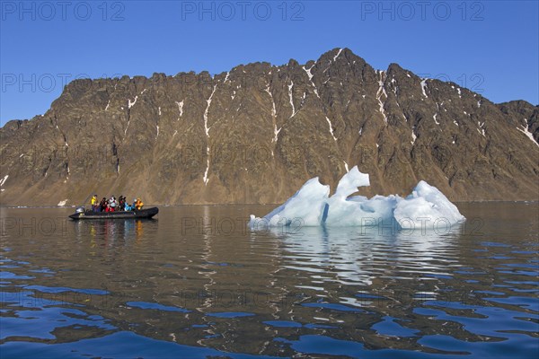 Eco-tourists in zodiac boat photographing melting iceberg in the Lilliehoeoekfjorden
