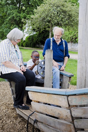 Temporary grandparents. Elderly couple volunteer to look after a boy from Africa for a few hours a week.