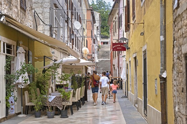 Tourists walking in alley with restaurants in the historic town centre of the city Pula