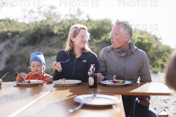 Summer party. Three generations eat together at one table.
