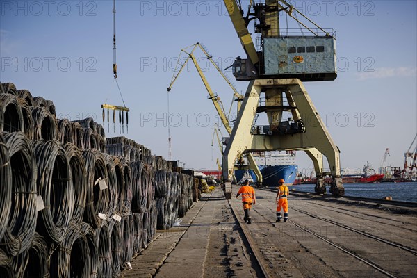 Dock workers walk past rolls of steel wire on the quay in Constanta harbour. Constanta