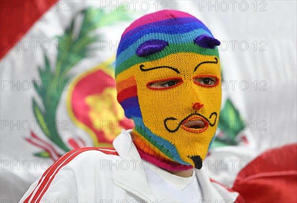 Peruvian fan with mask in front of flag Peru