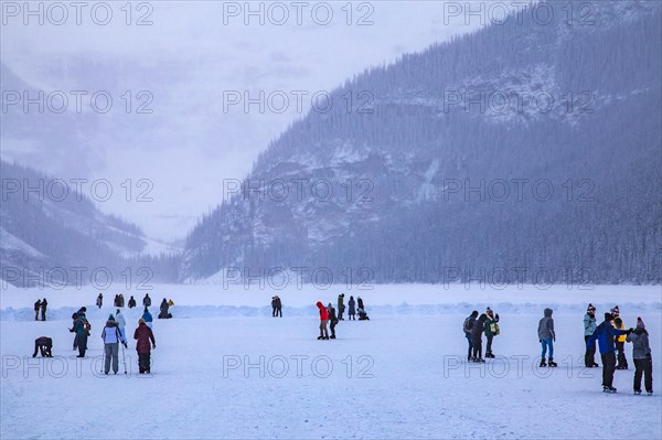 Ice skaters on the frozen mountain lake Lake Louise near Castle Hotel Chateau Lake Louise