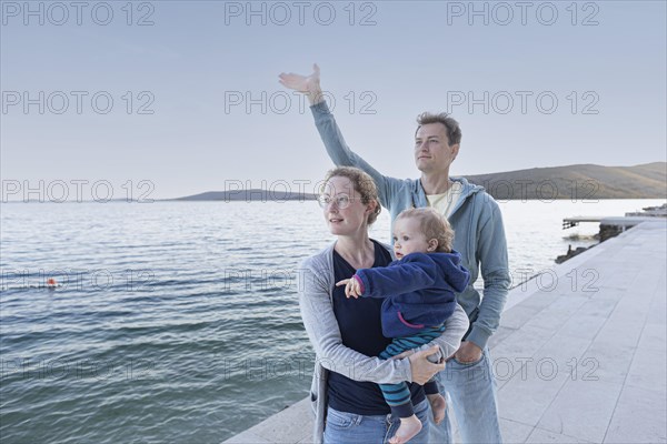 Family with small child standing by the sea